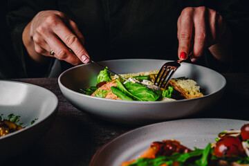 woman eating healthy salad from bowl sitting in cafe