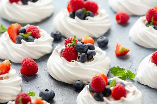 Meringue nest mini pavlova cake with fresh berries strawberry blueberry raspberry and mint for healthy desert.
