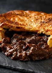 British beef steak pie with onion, wine gravy on rustic stone board