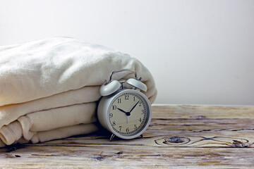 White alarm clock on a light wooden background, copy space.