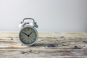 White alarm clock on a light wooden background, copy space.