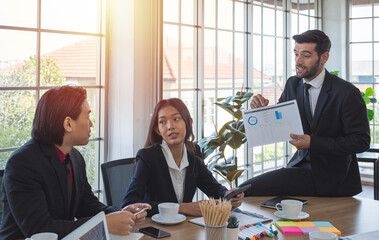 Caucasian business woman and asian co worker look and listen to man .colleague explain chart in meeting room.