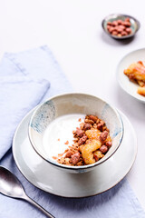 Healthy breakfast yogurt bowl with granola and caramelized bananas and nuts on grey concrete background. Selective focus
