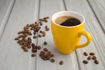 Black  coffee in the yellow cup on the gray wooden background
