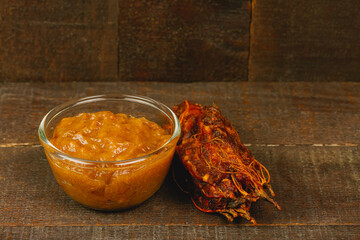 Tamarind juice in glass bowl and ripe tamarind tropical fruit on wooden background.