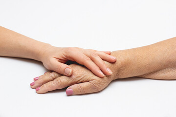 Old and young holding hands on light background, closeup