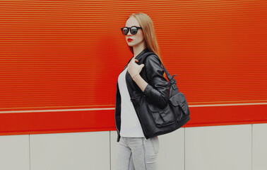 Naklejka premium Stylish woman with bag walking in the city on a red background