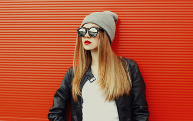 Portrait of young blonde woman in sunglasses on a red background