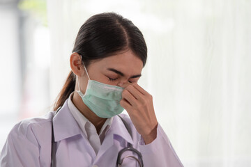 Young Asian female doctor suffering from a headache at work