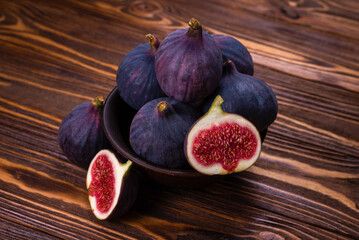 Tasty figs in a bowl on wooden background. Top view.