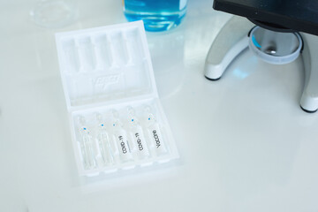 Coronavirus vaccine vials with group of chemical equipment in laboratory.