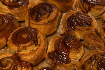 Homemade cinnamon buns with spices and caramel on parchment paper.