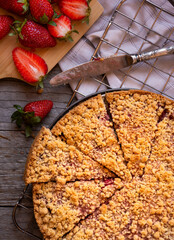 Delicious crumble cake with strawberry on wooden background