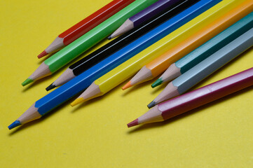 Fototapeta premium several multi-colored pencils lie on the yellow surface.
