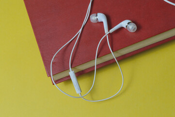 white small headphones and stack of books audiobook concept.
