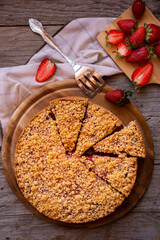 Delicious crumble cake with strawberry on wooden background