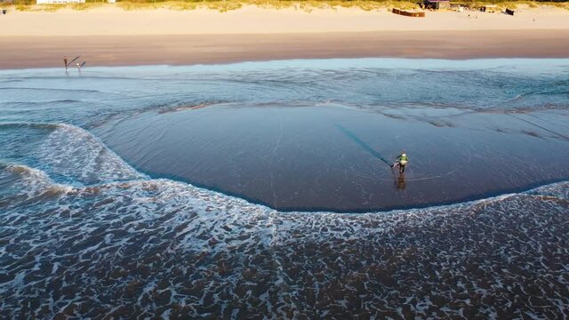 Fisherman battling the Waves during Sunset at Costa da Caparica beach, Portugal