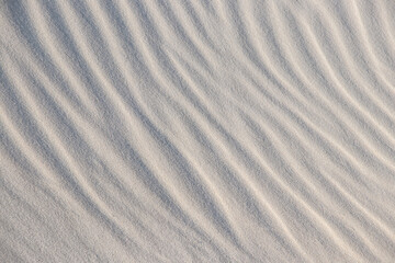 Natural background with patterns on the sand of dune. Background, sand, light, beige, wave, reflect, shadow, summer. Beautiful sand`s background with graphics waves, shadows and lights.