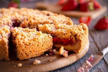 Delicious crumble cake with strawberry on wooden background