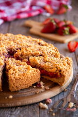 Delicious crumble cake with strawberry on wooden background
