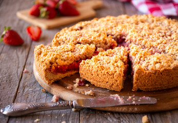 Delicious crumble cake with strawberry on wooden background