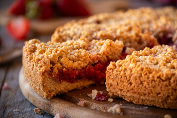 Delicious crumble cake with strawberry on wooden background
