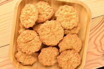 Several sweet torchetti cookies with oatmeal in a bamboo plate, close-up, on a wooden table.