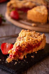 Delicious crumble cake with strawberry on wooden background
