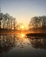 Golden Spring sunrise reflecting in a pond at the village green on a misty morning