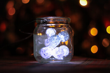 Transparent jar with led lights inside and Bokeh lights in background. Home decoration
