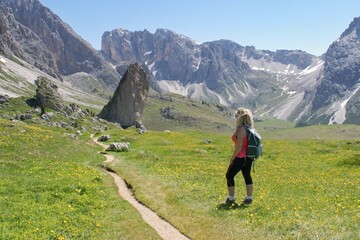 Woman hiker watching beautiful summer mountain scenery in Italian Dolomites .