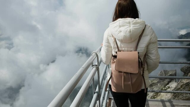 Woman tourist walking on the top of the mountain above the clouds. Amazing view of Lomnica Peak, High Tatras, Slovakia