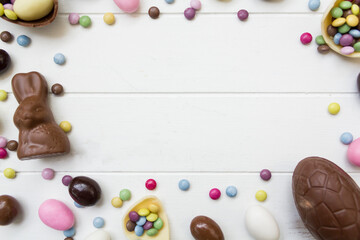Naklejka na ściany i meble Top view of easter composition with chocolate candies on white wooden table with copy space