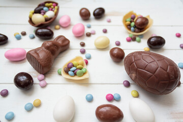 Easter candies on white wooden table. Chocolate eggs, chocolate bunny and other easter sweets