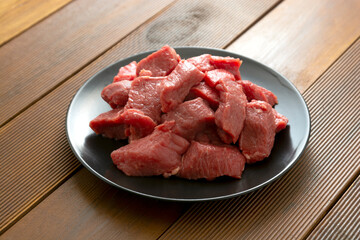 Beef uncooked raw steak on black plate, wooden board.