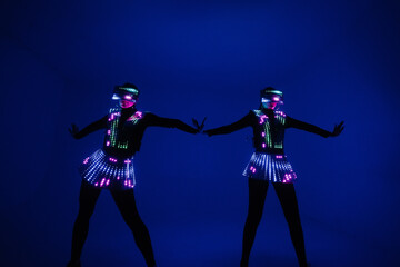 Two sexy disco dancers move in UV costumes. Parties and dances.