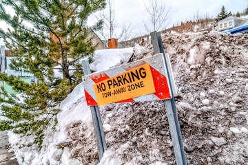 Traffic barrier with No Parking Tow-Away Zone sign on a snowy hill in winter