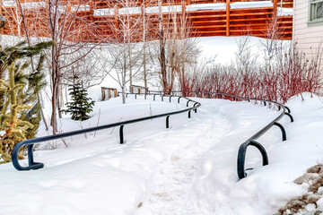 Fototapeta na wymiar Pathway with metal handrails covered with thick layer of white snow in winter