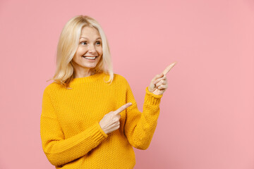 Funny elderly gray-haired blonde woman lady 40s 50s years old in yellow casual sweater pointing...