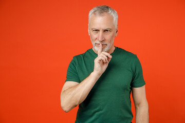 Secret elderly gray-haired mustache bearded man in basic green t-shirt saying hush be quiet with...
