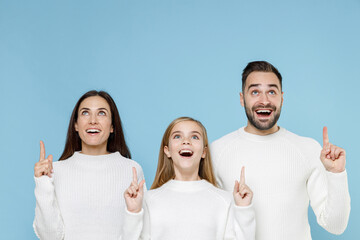 Surprised young parents mom dad with child kid daughter teen girl in white sweaters pointing index...