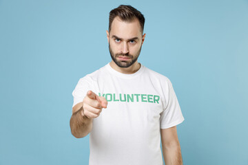 Displeased strict young bearded man in white volunteer t-shirt pointing index finger on camera...