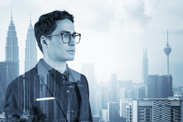 Young handsome businessman in suit and glasses dreaming about new career opportunities after MBA graduation. Kuala Lumpur on background. Double exposure.