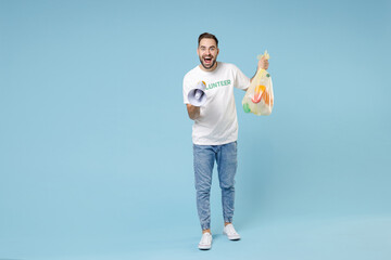 Fototapeta na wymiar Full length excited young man in white volunteer t-shirt jumping hold trash bag scream in megaphone isolated on blue background studio. Voluntary free assistance help trash sorting recycling concept.