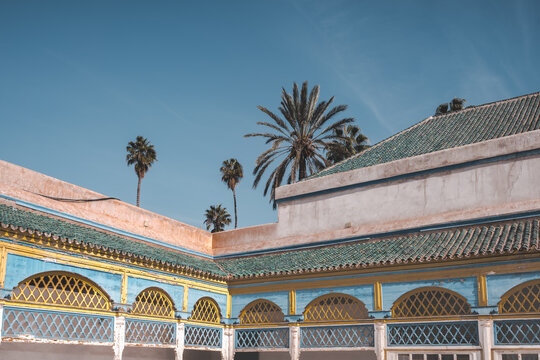 View to empty Courtyard and colorful traditional arabic patio at El Bahia Palace, Marrakech, Morocco. Travel concept photo on a sunny day with blue sky and no clouds. Palm trees in background.