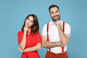 Pensive young couple two friends man woman in white red clothes put hand prop up on chin looking aside isolated on pastel blue color background studio portrait. St. Valentine's Day holiday concept.