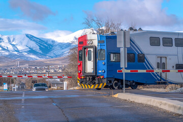 Train on railway and road intersection against snowy mountain and blue sky views