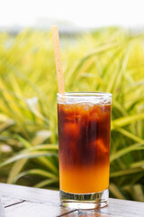 Iced fresh orange juice topped with espresso on wooden table in a garden; as sunrise coffee make a good day.