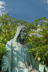 große Jesusskulptur inmitten eines Rhododendron 