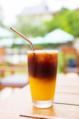 Iced fresh orange juice topped with espresso on wooden table in a garden; as sunrise coffee make a good day.